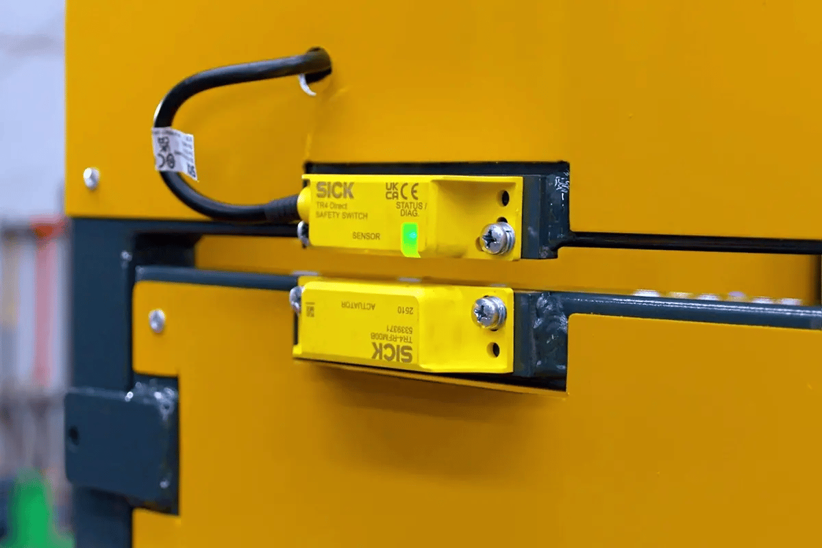 Close-up of the Wastech Slimline Bin Lifter key-lockable access gate and safety-rated interlock switch in the locked position