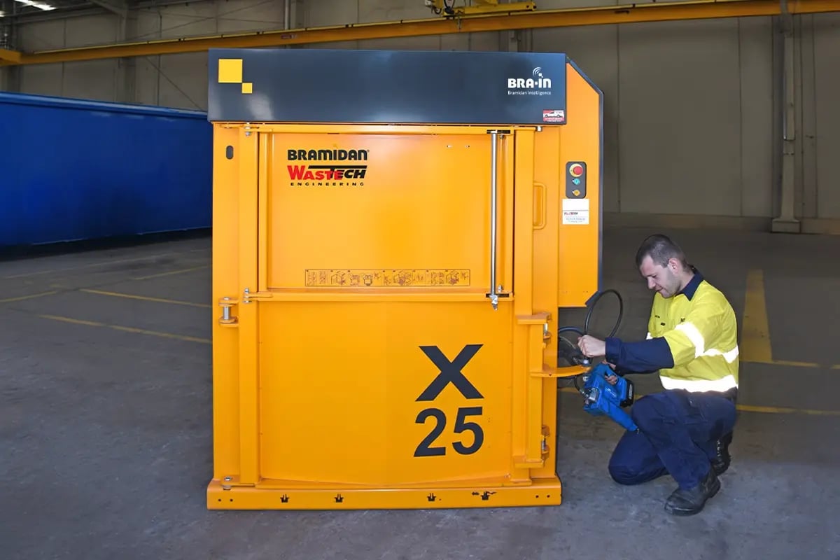 Wastech technician performing a scheduled maintenance check on waste equipment